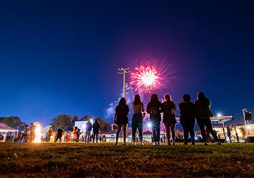 Alumni watching fireworks on football field.